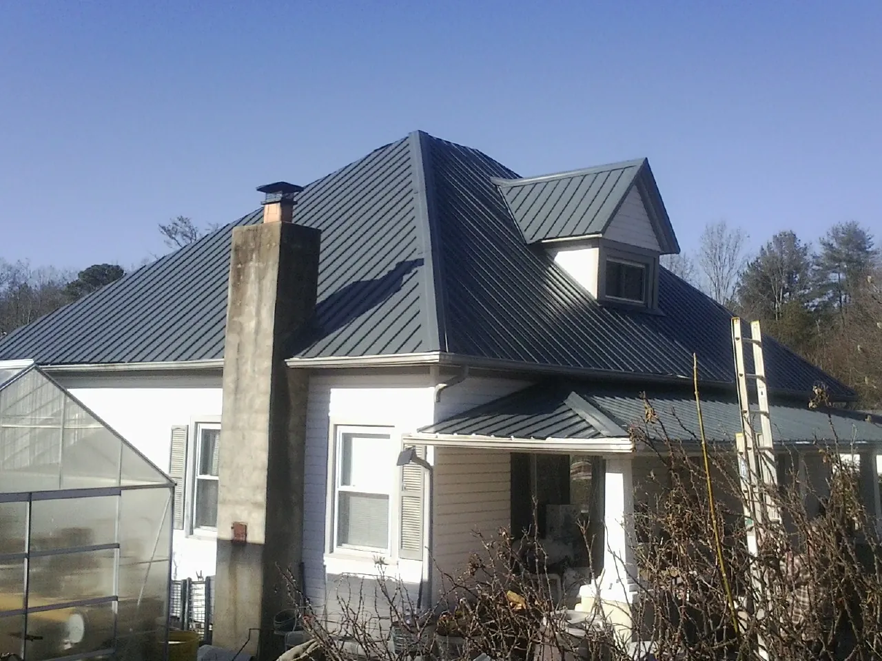 Dark blue standing seam metal roof on a white farmhouse with dormer — Slate & Tile Roof Repair by Roofing Brothers in Fountain Hills