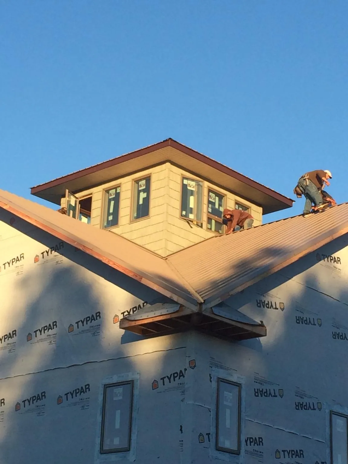 Roofers working around a rooftop cupola on a new metal roof at sunset — Roof Waterproofing in Fountain Hills by Roofing Brothers